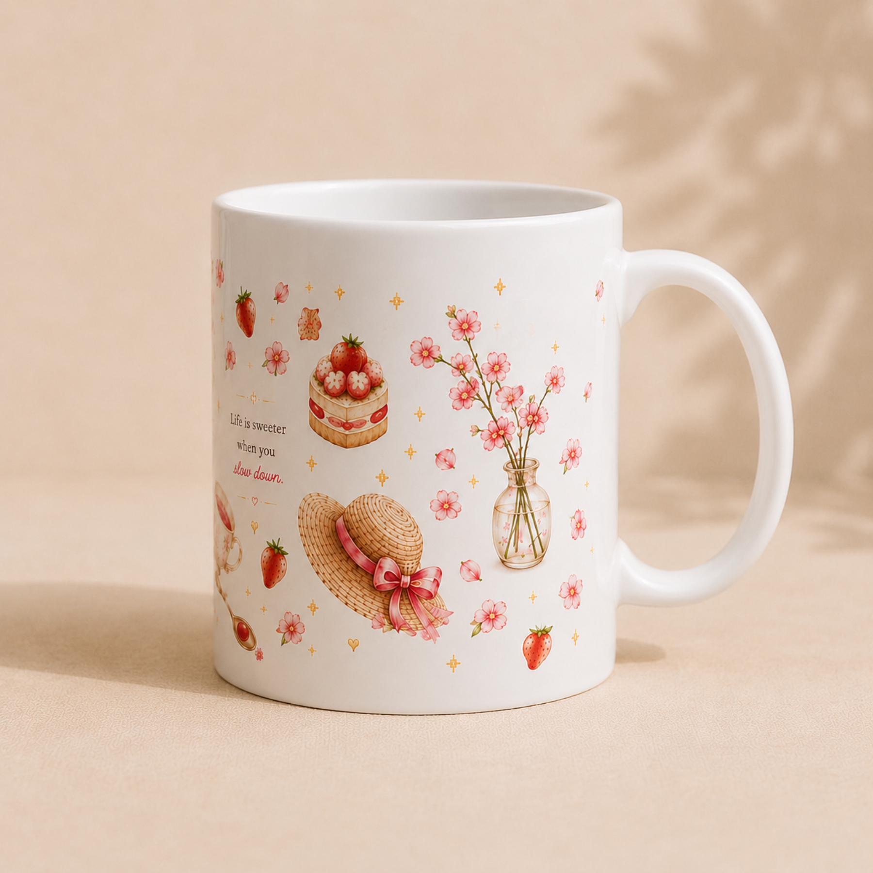 A white ceramic mug decorated with pink strawberries, a strawberry cake, a straw hat with a pink bow, and pink flowers in a glass vase, set against a warm beige background with soft leaf shadows.
