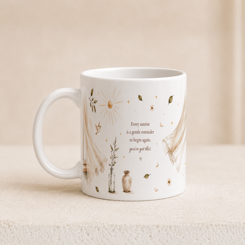 A white ceramic mug with a delicate beige and brown illustration of a sun, flowers, leaves, and lace, featuring the quote 'Every sunrise is a gentle reminder to begin again, you've got this.' It is set on a textured beige surface against a soft beige background.